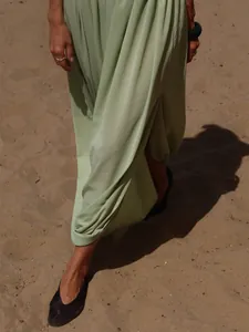 Gros plan d'une jupe longue vert clair à plis tulipe avec fente latérale sur sable
