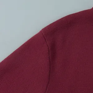 Macro detail view of the fine knit texture and shoulder seam on a burgundy slim sweater