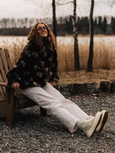 Woman wearing oversized floral fleece sweatshirt in a cozy outdoor lakeside setting