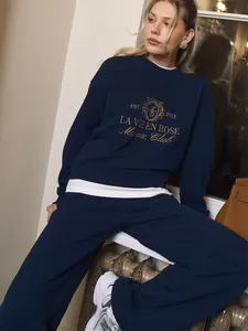 Chic model wearing a navy blue two-piece tracksuit set with premium golden embroidery.