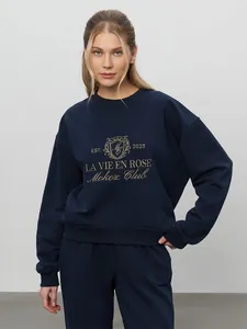 Close-up detail of navy blue sweatshirt featuring gold La Vie En Rose embroidery