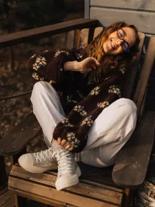 Detailed view of cozy brown floral fleece sweatshirt worn outdoors on a warm sunny day.