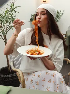 Donna con maglietta in cotone stampa croissant in un caffè all'aperto