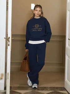 Model wearing navy blue embroidered sweatshirt and matching pants set with a brown handbag