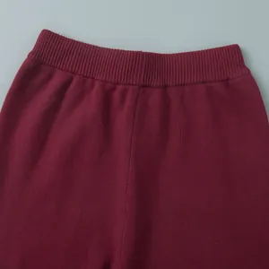 Close-up of the elastic ribbed waistband on burgundy knit trousers for a cozy fit.