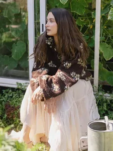 Detail view of woman in floral sherpa fleece pullover and long skirt in garden setting