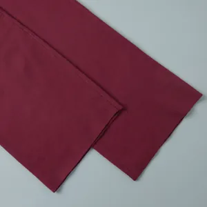 Close-up of burgundy knitted fabric texture showing fine rib knit and hem detail