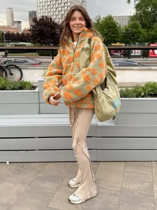 Young woman styling a trendy green and orange floral fleece sweatshirt outdoors