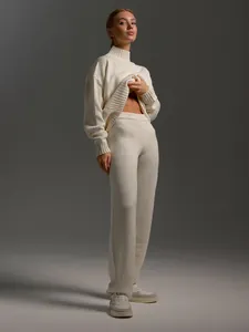 Detailed view of women's cream knit turtleneck sweater and matching knit trousers set