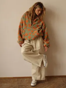 Detail view of a cozy green floral fleece hoodie paired with beige wide-leg pants and shoes
