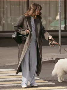 Street style model wearing a grey embroidered sweatshirt and sweatpants set with a long coat