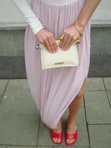 Détail de l'élégante jupe longue plissée tulipe rose clair avec fente latérale et drapé