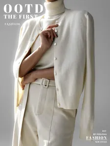 Detail shot of elegant cream knitwear set with turtleneck top and buttoned cardigan