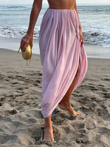 Vue détaillée de près d'une jupe longue drapée rose avec fente sur une plage de sable