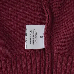 Close-up of maroon knitted sweater detailing the fabric texture and material care label.