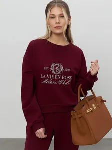 Detailed view of the burgundy embroidered sweatshirt set featuring a Mokoz Club crest design