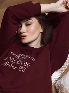 Close-up of burgundy embroidered sweatshirt with vintage-style white text detail.