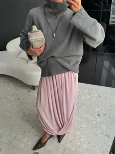 Élégante jupe longue tulipe plissée rose avec détails drapés, portée avec un col roulé gris