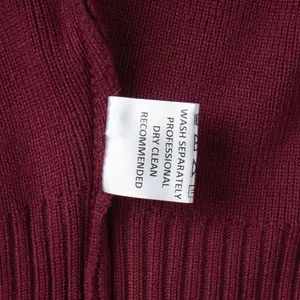 Macro detail of wash care label on a burgundy slim-fit knitted sweater set garment