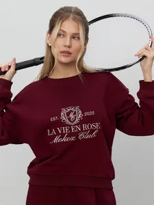 Detail view of the intricate white embroidery on a premium burgundy sweatshirt for women