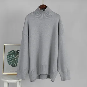 Vista dettagliata di un maglione grigio oversize a collo alto appeso a una gruccia in legno
