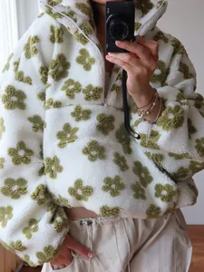Macro view showing the soft texture of a white sherpa hoodie with green floral patterns
