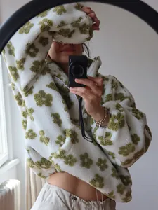 Close-up detail of white and green floral fleece hoodie with soft sherpa texture material