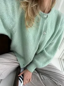 Detailansicht der mintgrünen Strickjacke mit weißen Knöpfen und weicher Flauschstruktur