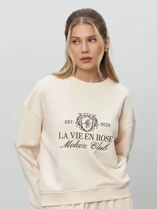 Detailed view of cream embroidered sweatshirt with vintage crest design