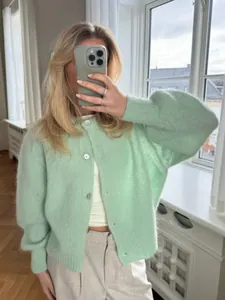 Eine Frau in einer weichen mintgrünen Mohair-Strickjacke macht ein Selfie im Spiegel