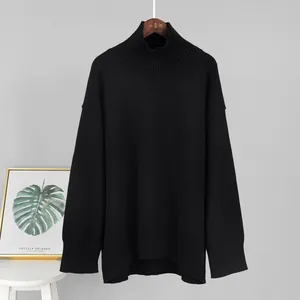 Vista completa di un maglione a collo alto nero in maglia larga appeso al muro