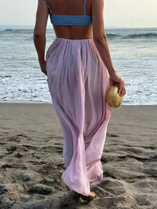 Vue arrière d'une élégante jupe longue tulipe plissée rose clair sur la plage.