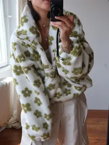Close-up of white fleece floral sweatshirt with olive green flower patterns and half-zip