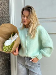 Modell trägt einen mintgrünen Strickcardigan mit einer Knopfleiste und Blumen