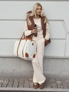 Model wearing cream embroidered sweatshirt and matching pants in a casual street setting