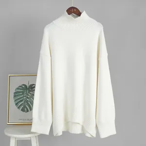 Primo piano di un maglione a dolcevita bianco oversize appeso a una gruccia di legno.
