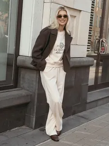 Full-body street style view of a cream embroidered sweatshirt and wide-leg pants set.
