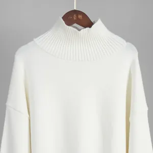 Primo piano del maglione bianco a collo alto con dettaglio della trama a coste premium