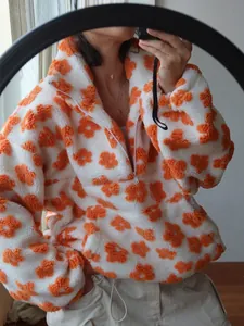 Detail of cozy sherpa fleece sweatshirt with orange floral pattern and half-zip collar