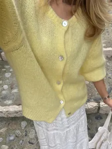 Detailansicht einer hellgelben, einreihigen Strickjacke mit edlen Perlmuttknöpfen