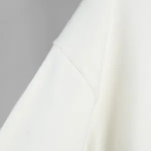 Primo piano di un maglione di maglia bianco che mostra la trama fine del tessuto e le cuciture