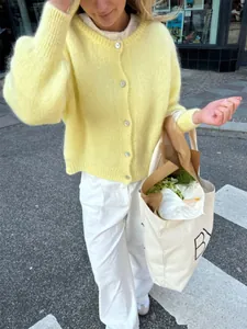 Süße gelbe Strickjacke mit einreihiger Knopfleiste in einem Street-Lifestyle-Shooting