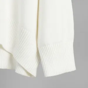 Dettaglio ravvicinato di un maglione lavorato a maglia bianco con polsini a coste