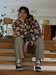 Woman wearing a gray floral pattern fleece hoodie in a lifestyle indoor setting