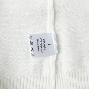 Detailaufnahme des Pflegeetiketts für weiße Strickweste mit Material und Größe S