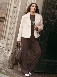 Lifestyle detail of embroidered sweatshirt and matching pants with cream coat