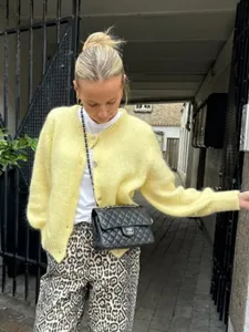Detailaufnahme eines gelben Strick-Cardigans über einem weißen T-Shirt und Leopardenhose