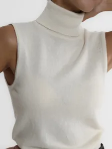 Macro view of a white turtleneck knit vest showing the soft ribbed texture and fit.