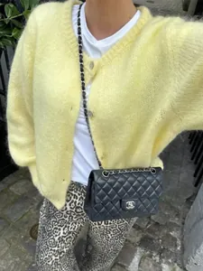 Nahaufnahme einer flauschigen gelben Strickjacke mit eleganten einreihigen Knöpfen.