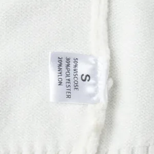 Primo piano dell'etichetta del maglione bianco con taglia S e composizione materiale